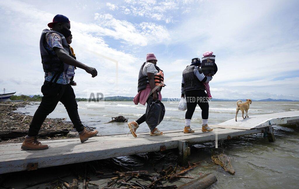 Fernando Vergara Haitian migrants walk on the dock to a boat that will take them to Acandi, near the border with Panama, as they depart Necocli, Colombia, Monday, Sept. 13, 2021. Migrants have been gathering in Necocli as they move north on their way to the U.S. border. (AP Photo/Fernando Vergara)