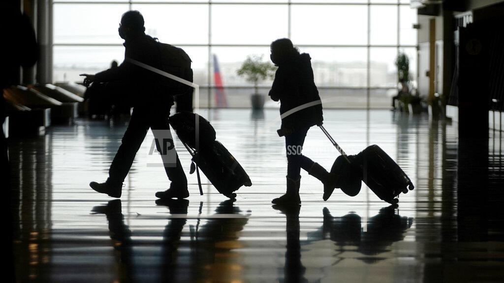 FILE - In this Tuesday, March 9, 2021 file photo, travelers walk through the Salt Lake City International Airport, in Salt Lake City. The number of people flying in the United States has eclipsed the year-ago level for the first time in the pandemic period, although travel remains deeply depressed from 2019. The Transportation Security Administration said 1.34 million people passed through U.S. airport checkpoints on Sunday, March 14 topping the 1.26 million people that TSA screened on the comparable Sunday a year ago. (AP Photo/Rick Bowmer, File)