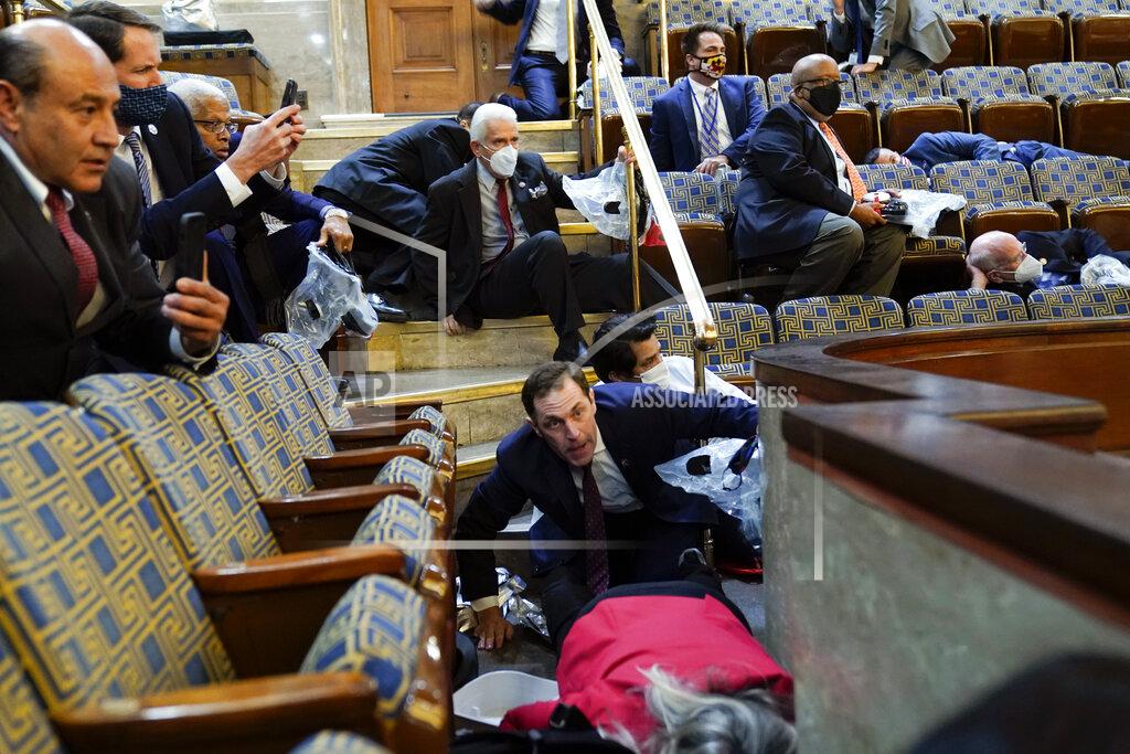 Andrew Harnik FILE - In this Jan. 6, 2021, file photo people shelter in the House gallery as rioters try to break into the House Chamber at the U.S. Capitol. Arguments begin Tuesday, Feb. 9, in the impeachment trial of Donald Trump on allegations that he incited the violent mob that stormed the U.S. Capitol on Jan. 6. (AP Photo/Andrew Harnik, File)
