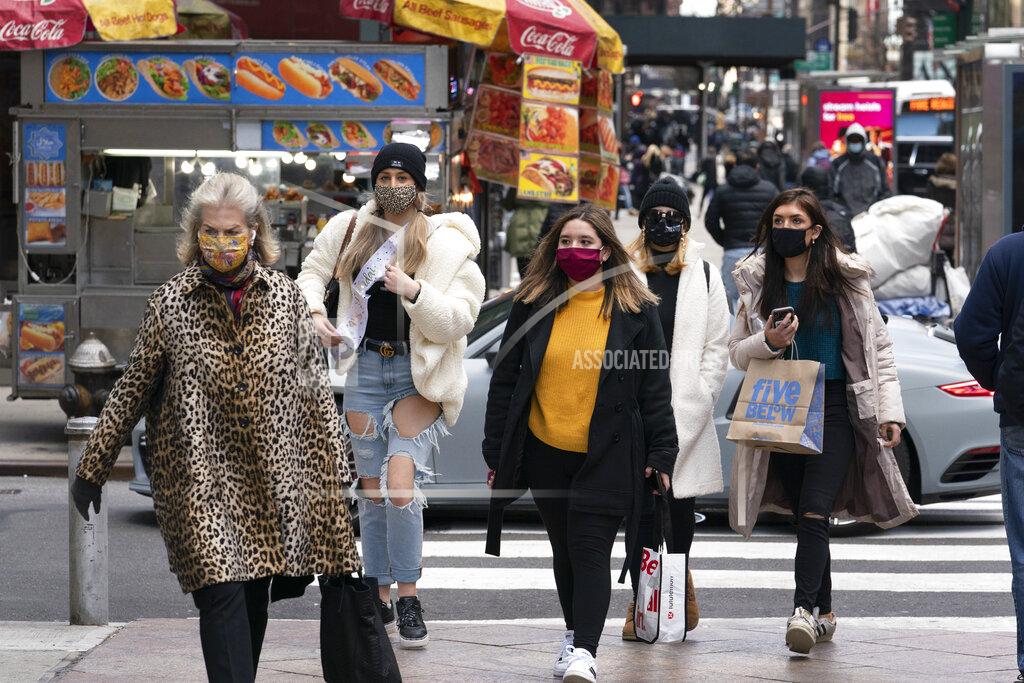 Mark Lennihan Women carry shopping bags, Thursday, Dec. 10, 2020, in New York. The spread of COVID-19 vaccines will power a stronger global economic recovery in 2021, the International Monetary Fund forecast Tuesday, Jan. 26, 2021. (AP Photo/Mark Lennihan)