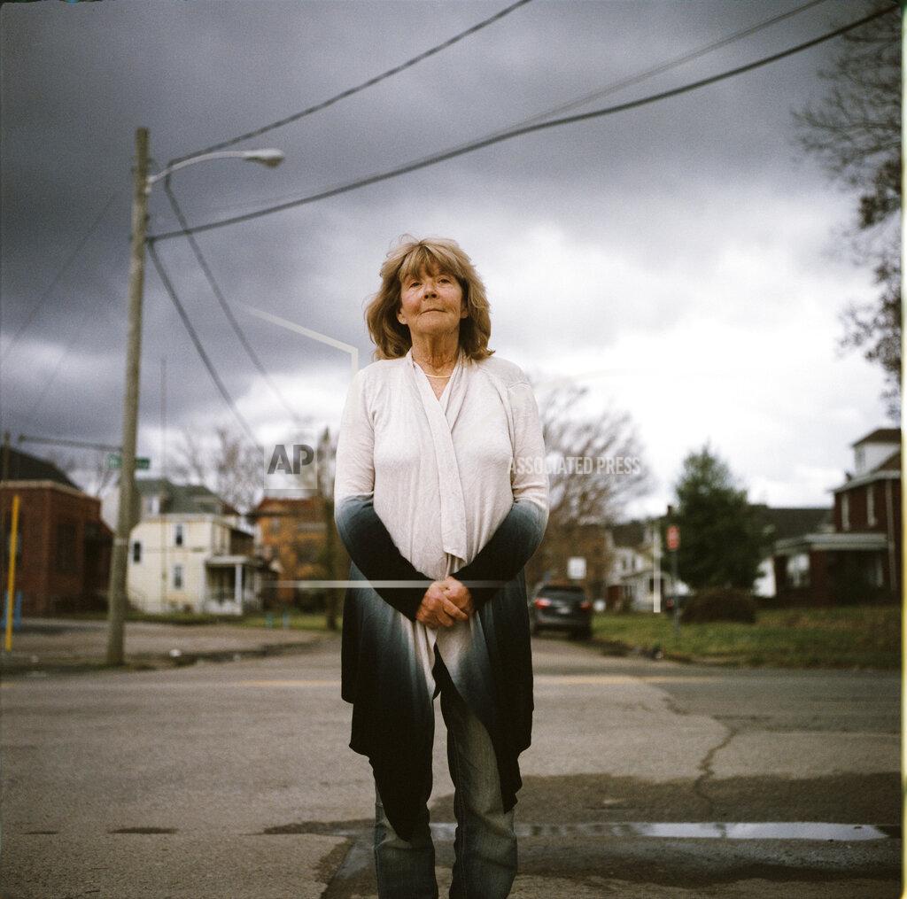 David Goldman In this photo made with a medium format film camera, Sue Howland, a member of the Quick Response Team that tries to track down everyone who overdoses to offer help, stands for a portrait in Huntington, W.Va., Thursday, March 18, 2021. The 62-year-old peer recovery coach nearly drank herself to death years ago, so she can relate to the madness her clients are facing. "We're going to love them until they learn to love themselves. We're going to love them back to life," said Howland, who's been sober now for 10 years. "The things that bring me the greatest pleasures now are priceless: waking up in the morning, the sunrise, being able to walk on a beach, hearing the birds sing, seeing a rainbow, seeing raindrops fall in puddles, seeing somebody smile. I tell people when they come into treatment, I say you're giving yourself a gift money can't buy." (AP Photo/David Goldman)