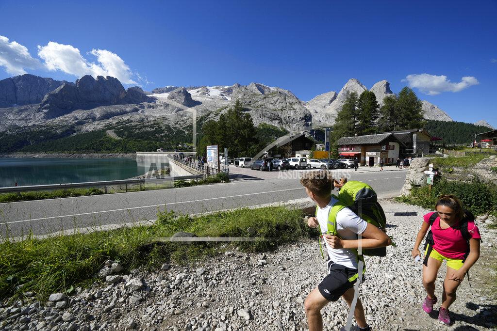 Luca Bruno Hikers walk past the Marmolada mountain and the Punta Rocca glacier near Canazei, in the Italian Alps in northern Italy, Wednesday, July 6, 2022, where an avalanche broke loose on Sunday, sending tons of ice, snow, and rocks onto hikers. (AP Photo/Luca Bruno)
