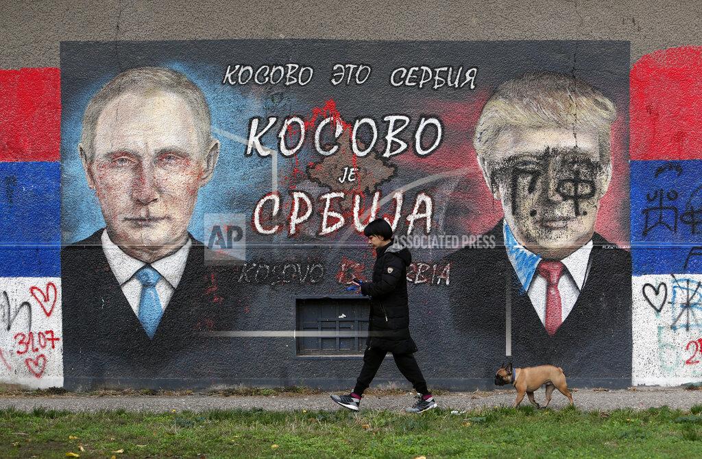 Darko Vojinovic A woman with a dog passes by graffiti depicting the Russian President Vladimir Putin, left, and U.S. President Donald Trump vandalized with paint in a suburb of Belgrade, Serbia, Tuesday, Nov. 3, 2020. The Cyrillic letters on graffiti read "Kosovo is Serbia". For some Serbian leaders, U.S. President Donald Trump is a hero while his challenger Joe Biden is nothing but a "Serb hater." So, there is no surprise that Serbs living in the U.S. were called on to vote for Trump in Tuesday's election nor that Serbia's populist president said his victory would be better for the country. (AP Photo/Darko Vojinovic)
