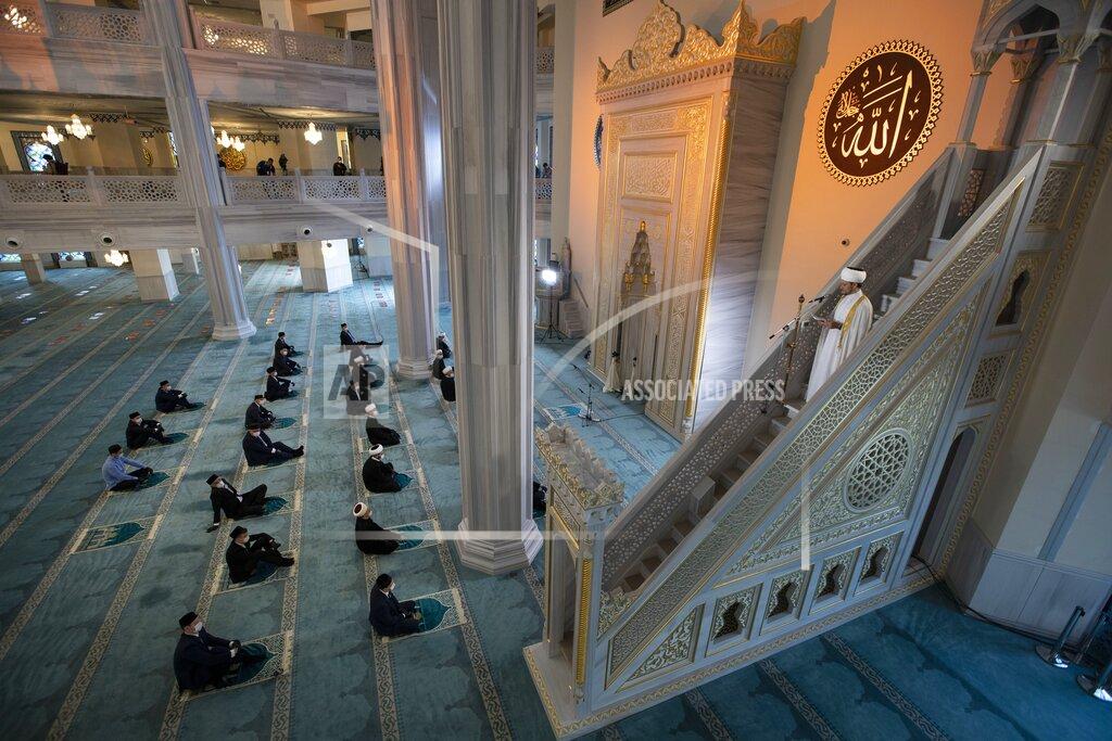 Mullahs wearing masks to help stop the spread of the coronavirus wait for Eid al-Adha prayer while maintaining a social distance at the almost empty main Mosque in Moscow, Russia, Friday, July 31, 2020. Eid al-Adha, or Feast of Sacrifice, Islam's most important holiday, marks the willingness of the Prophet Ibrahim to sacrifice his son. (AP Photo/Alexander Zemlianichenko)