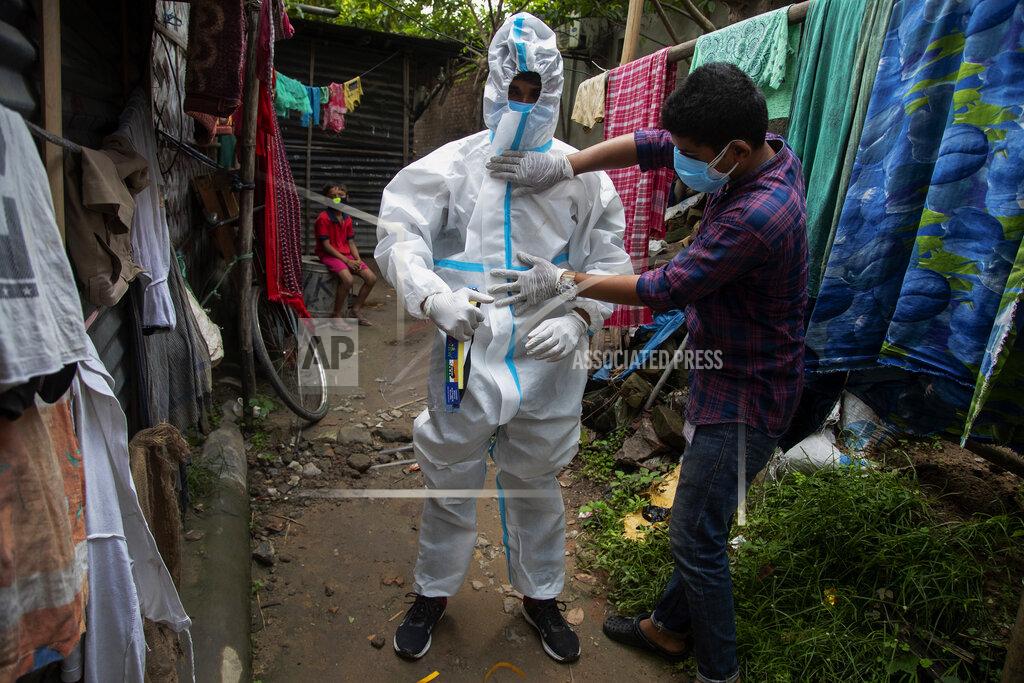 Anupam Nath A heath worker helps another to wear protective suit before collecting swab samples of people to test for COVID-19 in Gauhati, Assam, India, Monday, May 17, 2021. (AP Photo/Anupam Nath)