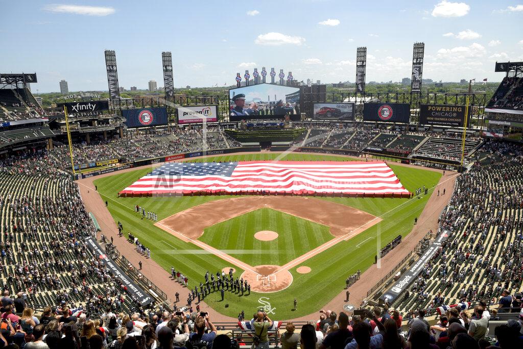 FILE - In this July 4, 2019, file photo, an American Flag is unfurled in the outfield during the playing of the National Anthem before the start a baseball game between the Chicago White Sox and the Detroit Tigers in Chicago. Thousands of fans of the Chicago Cubs and the Chicago White Sox will get to see their teams play in person this season, Mayor Lori Lightfoot announced on Monday, March 9, 2021. In a news release, Lightfoot said each team will be limited to 20% capacity. (AP Photo/Mark Black, File)
