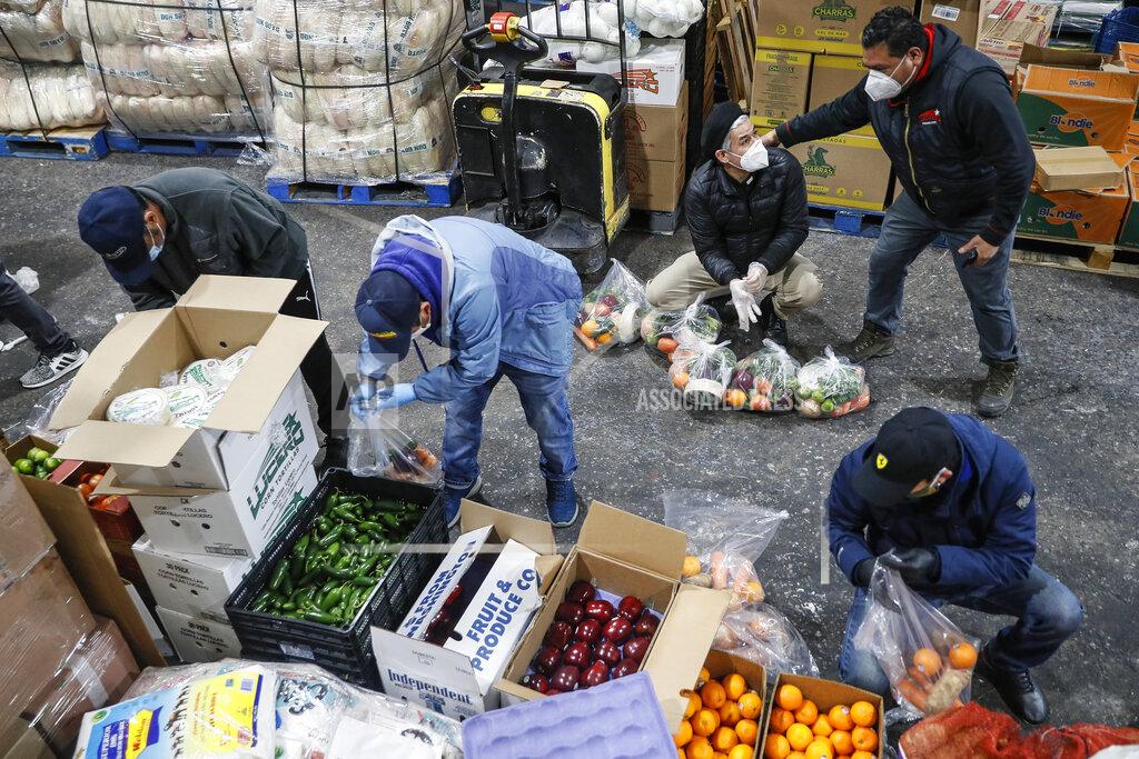 John Minchillo Fabian Arias, a Lutheran pastor with Saint Peter's Church in Manhattan, center right, coordinates with volunteers as they prepare food delivery donations at a produce wholesaler, Friday, May 8, 2020, in the Bronx borough of New York. (AP Photo/John Minchillo)