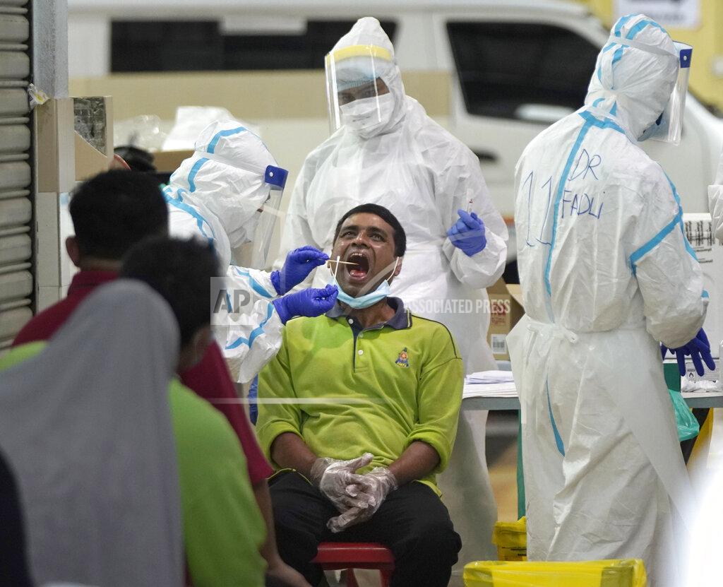 Vincent Thian A health worker collects sample for coronavirus testing from a worker at a locked down wet market as one of its traders tested positive for COVID-19 in Petaling Jaya, Malaysia, Tuesday, April 28, 2020. The Malaysian government issued a restricted movement order to the public till April 28, to help curb the spread of the new coronavirus. (AP Photo/Vincent Thian)