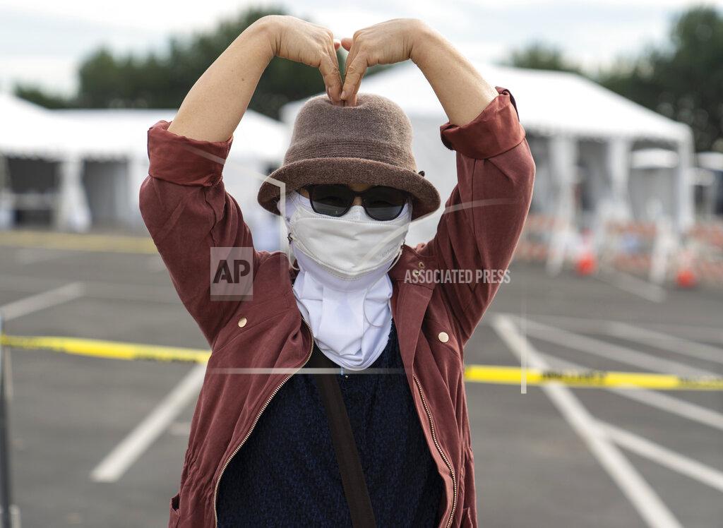 Damian Dovarganes Orange County resident Esther Song expresses her gratitude with a "Love" gesture after getting her vaccine at the Disneyland Resort serving as a Super POD (Point Of Dispensing) COVID-19 mass vaccination site Wednesday, Jan. 13, 2021, in Anaheim, Calif. The parking lot is located off Katella Avenue and sits southeast of Disneyland. California is immediately allowing residents 65 and older to get scarce coronavirus vaccines, Gov. Gavin Newsom announced Wednesday. (AP Photo/Damian Dovarganes)