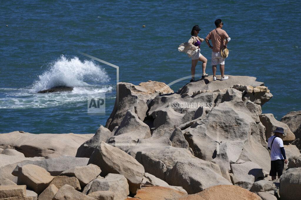 Ng Han Guan Tourists stand on rocks on the waterfront at the 68-nautical-mile scenic spot, the closest point in mainland China to the island of Taiwan, in Pingtan in southeastern China's Fujian Province, Friday, Aug. 5, 2022. China says it summoned European diplomats in the country to protest statements issued by the Group of Seven nations and the European Union criticizing threatening Chinese military exercises surrounding Taiwan. (AP Photo/Ng Han Guan)
