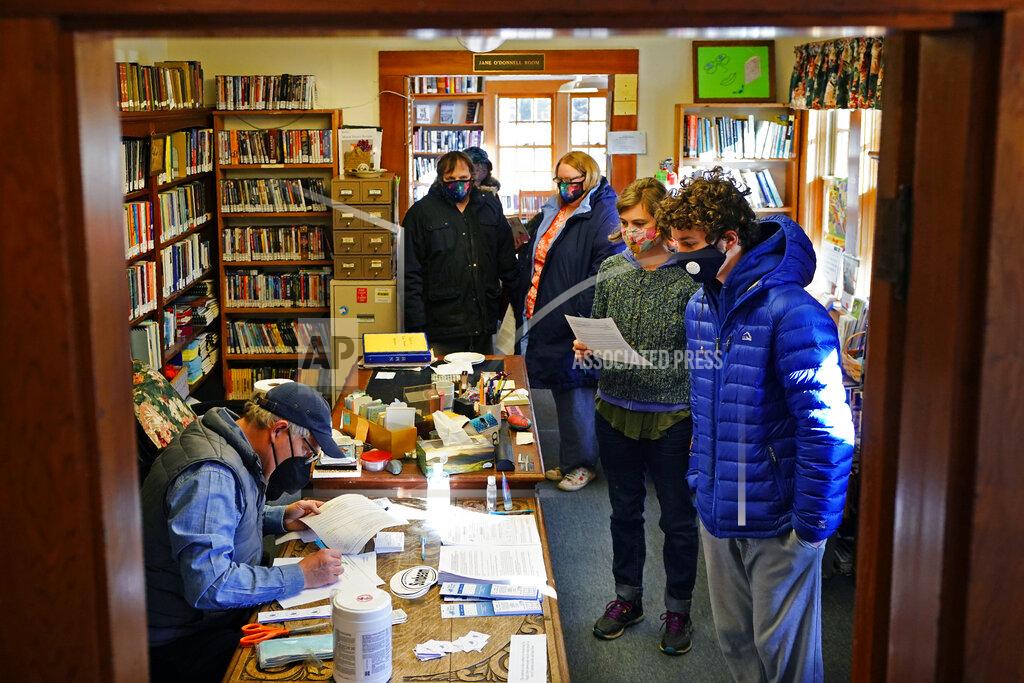 Robert F. Bukaty John Zavodny, president of the Maine Seacoast Mission, left, registers residents for COVID-19 vaccinations in a library on the island of Islesford, Maine, Friday, March 19, 2021. "Life on the islands is remote. And it's isolated. And I think that isolation is both the attraction but the heart of the challenge," said Zavodny said. (AP Photo/Robert F. Bukaty)