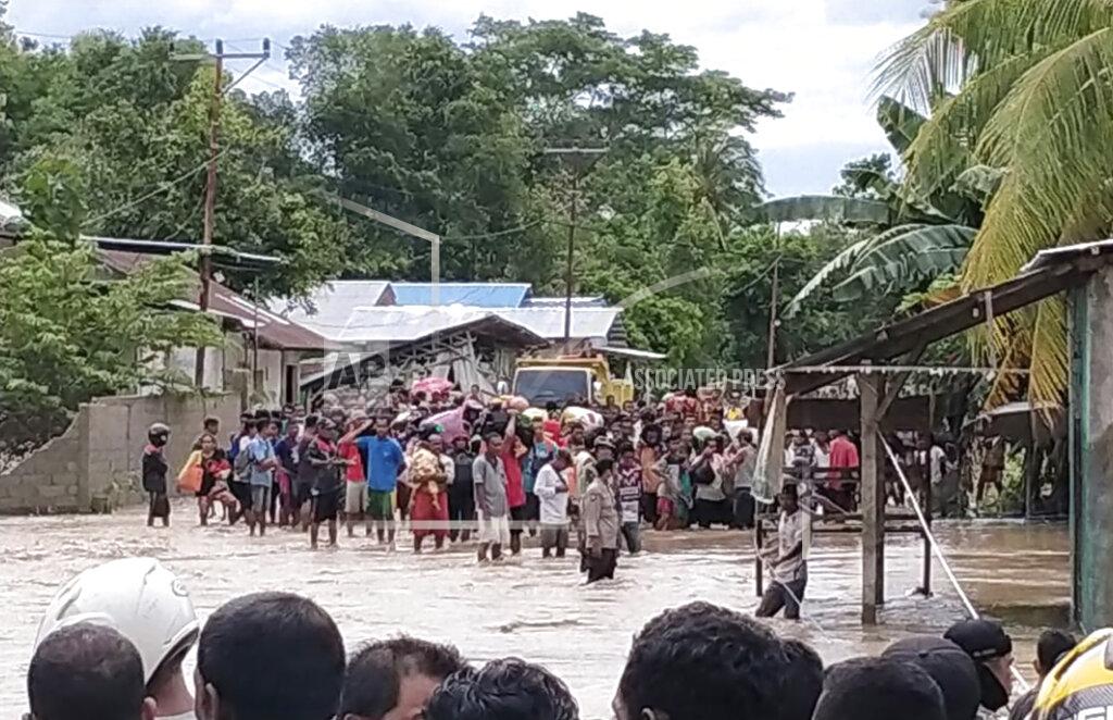 Uncredited Residents wait for help to cross a flooded road in Malaka Tengah, East Nusa Tenggara province, Indonesia, Monday, April 5, 2021. Multiple disasters caused by torrential rains in eastern Indonesia have left dozens of people dead and missing and displaced thousands, the country's disaster relief agency said Monday. (AP Photo)