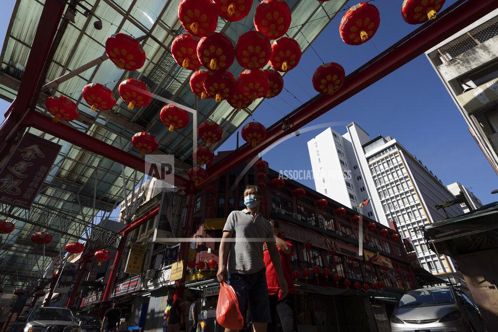 Vincent Thian A Chinese couple wear face mask walks with Chinese lunar new year decoration at China town in Kuala Lumpur, Malaysia, Sunday, Feb. 7, 2021. The movement control order (MCO) currently enforced across the country, has been extended to Feb. 18, effectively covering the Chinese New Year festival that falls on Feb. 12 this year. (AP Photo/Vincent Thian)