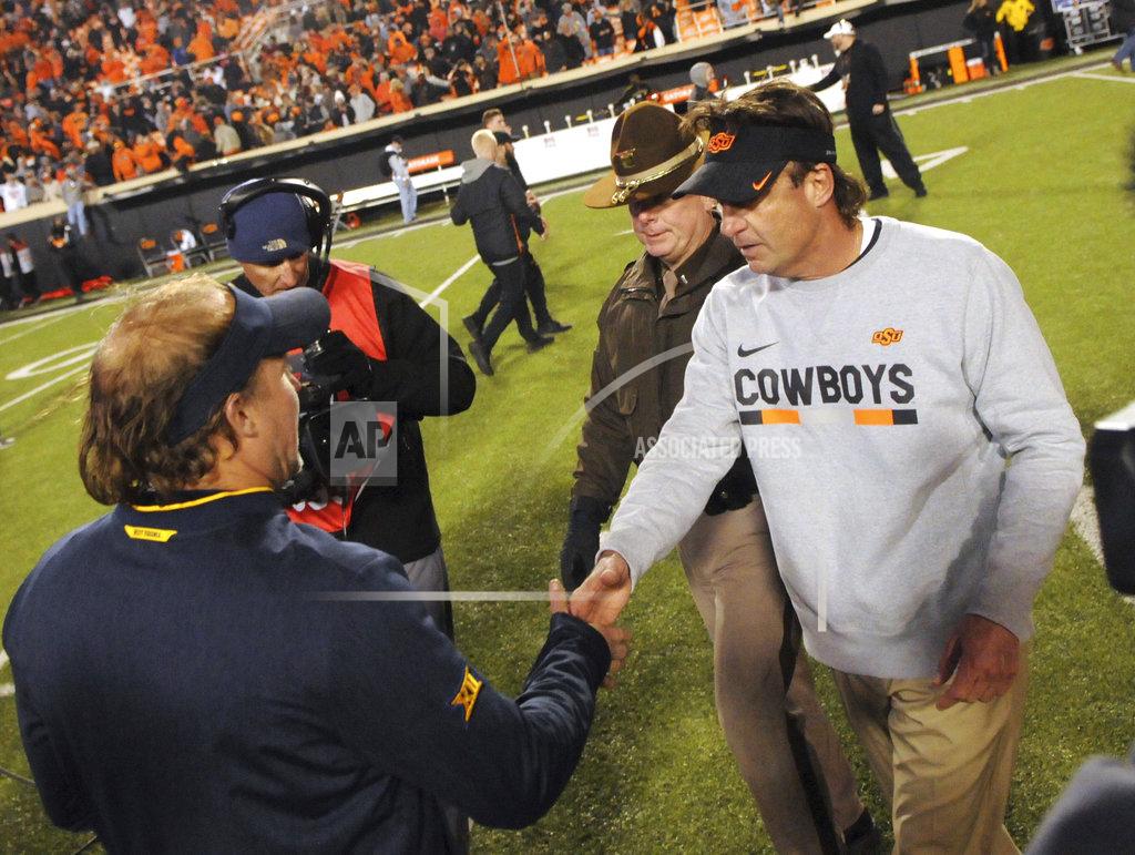 Brody Schmidt Oklahoma State head coach Mike Gundy, left, shakes the hand of West Virginia head coach Dana Holgorsen following an NCAA college football game in Stillwater, Okla., Saturday, Nov. 17, 2018. Oklahoma State defeated West Virginia 45-41. (AP Photo/Brody Schmidt)