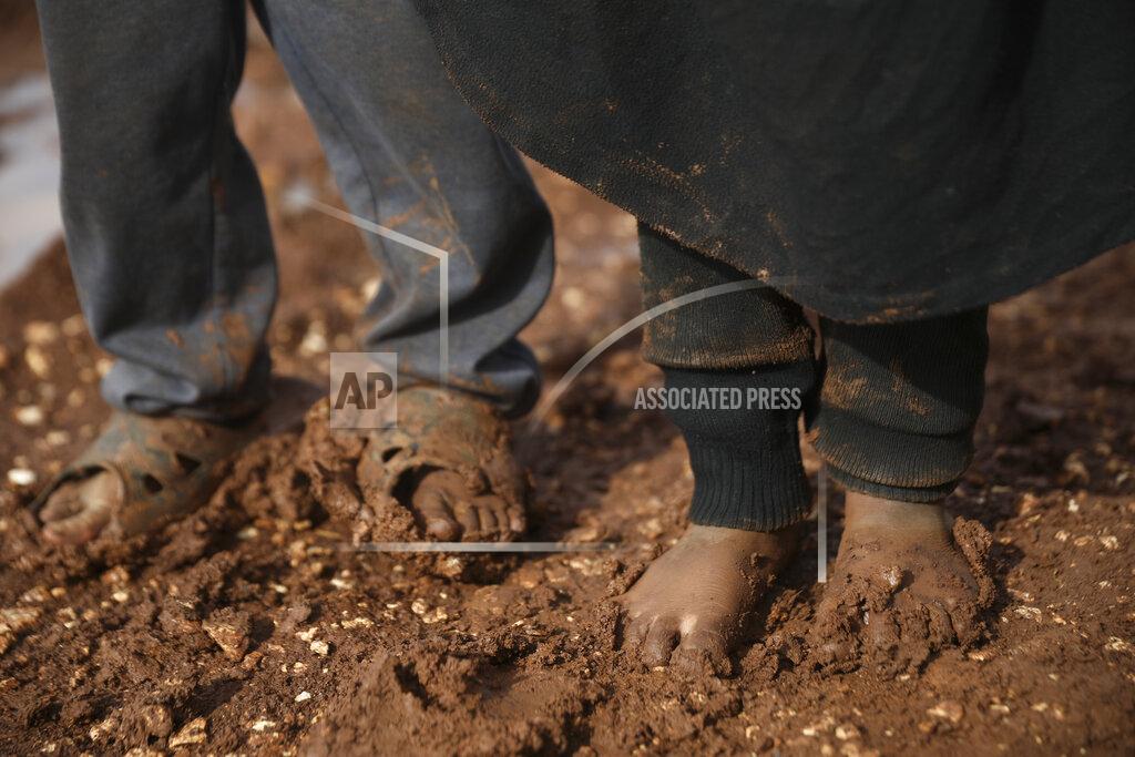 Syrian children stand in a camp for displaced muddied by recent rains near the village of Kafr Aruq , in Idlib province, Syria, Thursday, Jan. 28, 2021. (AP Photo/Ghaith Alsayed)