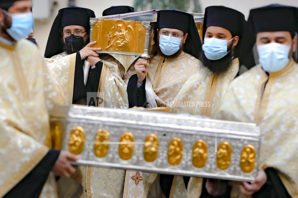 Vadim Ghirda Priests, wearing masks against the COVID-19 infection, carry the remains of Saint Dimitrie Bassarabov, the patron saint of the Romanian capital, on the first of three days of pilgrimage, taking place at a much smaller scale than usual, due to the pandemic control imposed measures, in Bucharest, Romania, Sunday, Oct. 25, 2020. Romania's daily tally of coronavirus infections rose above 5,000 for the first time last week and patients in intensive care units also reached a new high. (AP Photo/Vadim Ghirda)