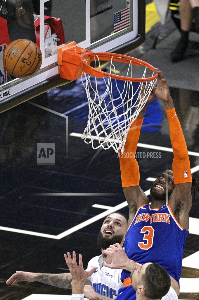 Phelan M. Ebenhack New York Knicks center Nerlens Noel (3) is fouled by Orlando Magic guard Evan Fournier, left, while going for a dunk as Magic center Nikola Vucevic, front, watches during the second half of an NBA basketball game Wednesday, Feb. 17, 2021, in Orlando, Fla. (AP Photo/Phelan M. Ebenhack)