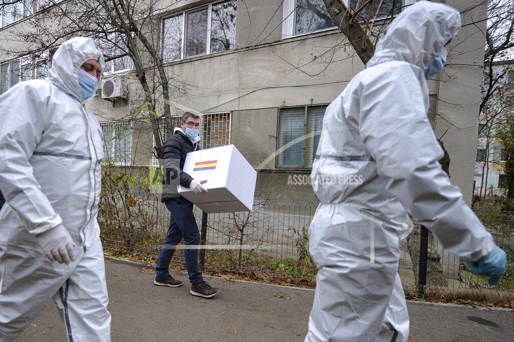 Alexandru Dobre Election officials, some wearing protective suits against the COVID-19 infection, take a mobile ballot box to people with mobility issues or quarantined in Bucharest, Romania, Sunday, Dec. 6, 2020. Voting started in Romania's legislative election expected to restore some measure of stability after five years of political and social turbulence with more than 18 million Romanians registered to vote for a new legislative body. (AP Photo/Alexandru Dobre)