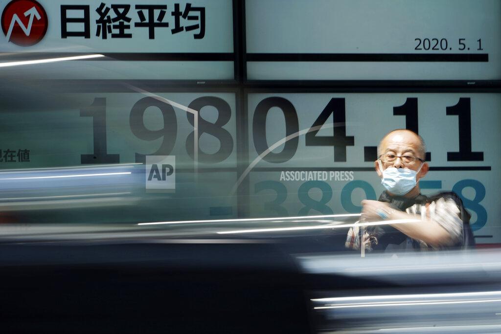 A man stands in front of an electronic stock board showing Japan's Nikkei 225 index at a securities firm in Tokyo Friday, May 1, 2020. Shares have dropped in Asia after Wall Street ended its best month in 33 years with losses on fresh news of economic carnage from the coronavirus pandemic. (AP Photo/Eugene Hoshiko)