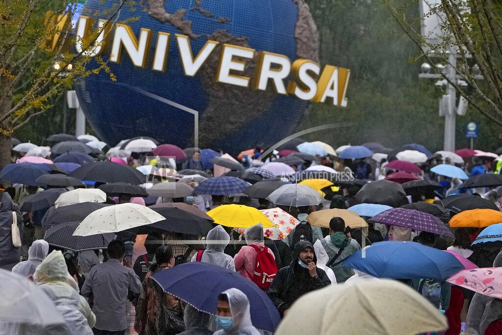 Andy Wong People wearing raincoats and carrying umbrellas walk through a plaza near the entrance of Universal Studios Beijing in Beijing, Monday, Sept. 20, 2021. Thousands of people brave the rain visit to the newest location of the global brand of theme parks which officially opens on Monday. (AP Photo/Andy Wong)