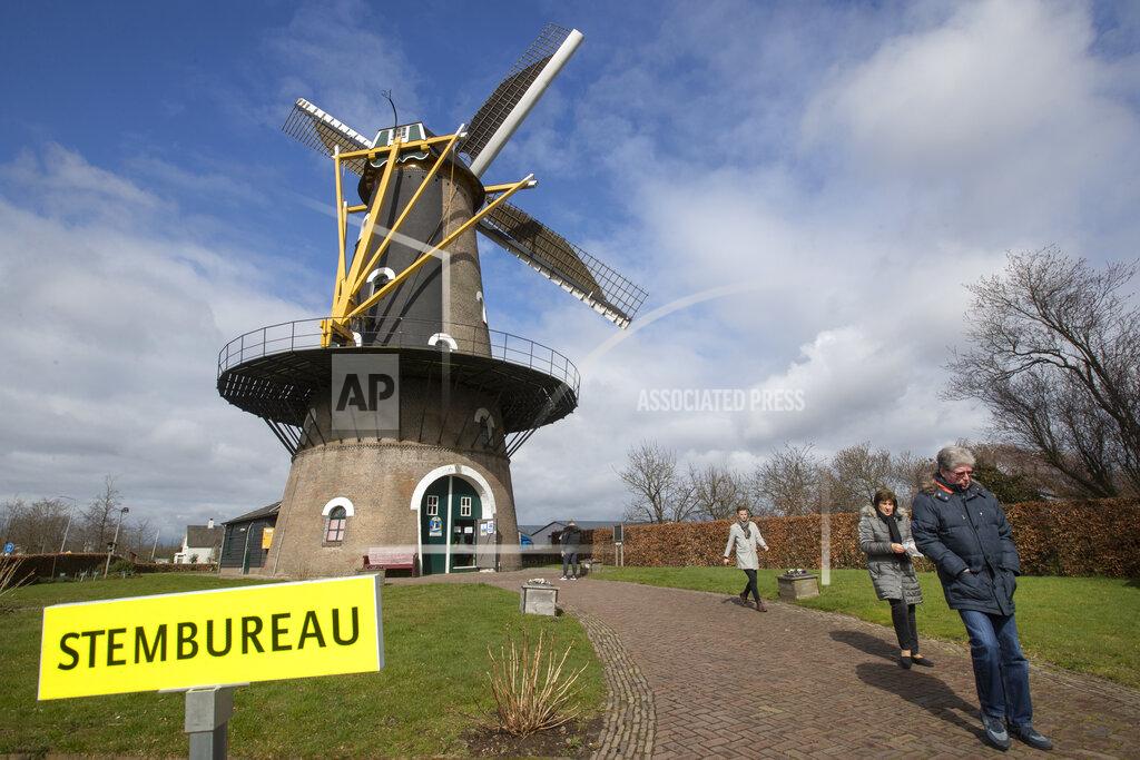 Peter Dejong Voters pass a sign reading "polling station" after casting their ballot at windmill the Kerhovense Molen during general election in Oisterwijk, Netherlands, Wednesday, March 17, 2021. Polling stations have opened opened across the Netherlands from Monday in a general election that has been spread over three days to allow people to vote safely during the coronavirus pandemic. (AP Photo/Peter Dejong)
