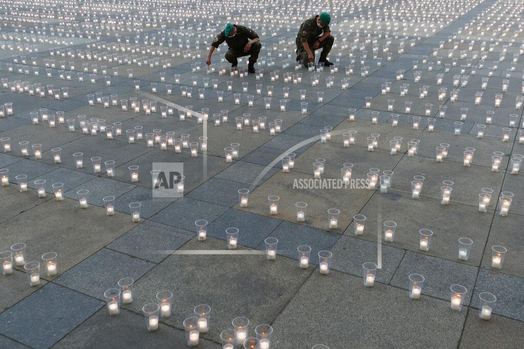 Petr David Josek Soldiers light up candles to commemorate victims of the COVD-19 pandemic at the Prague Castle in Prague, Czech Republic, Monday, May 10, 2021. The Czech Republic is massively relaxing its coronavirus restrictions as the hard-hit nation pays respect to nearly 30,000 dead. (AP Photo/Petr David Josek)