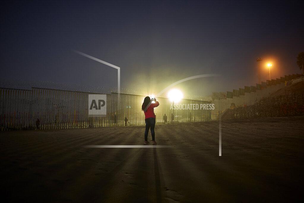 Gregory Bull FILE- A woman records with her phone, as floodlights from the United States light up the newly-fortified border wall Thursday, Jan. 10, 2019, along the beach in Tijuana, Mexico. Top Trump administration officials will visit South Texas five days before Election Day to announce they have completed 400 miles of U.S.-Mexico border wall, attempting to show progress on perhaps the president's best-known campaign promise four years ago. But most of the wall went up in areas that already had smaller barriers. (AP Photo/Gregory Bull)