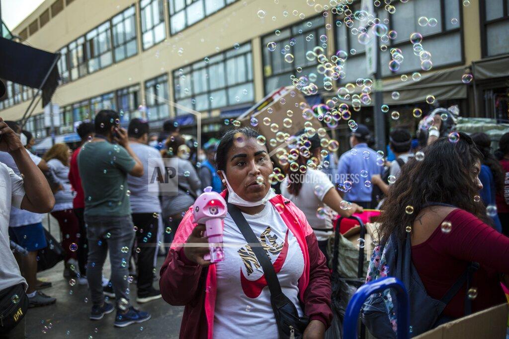 Rodrigo Abd A street vendor sells a device that makes bubbles at the Mesa Redonda Market, a popular spot for Christmas shopping, amid the COVID-19 pandemic in Lima, Peru, Monday, Dec. 21, 2020. (AP Photo/Rodrigo Abd)