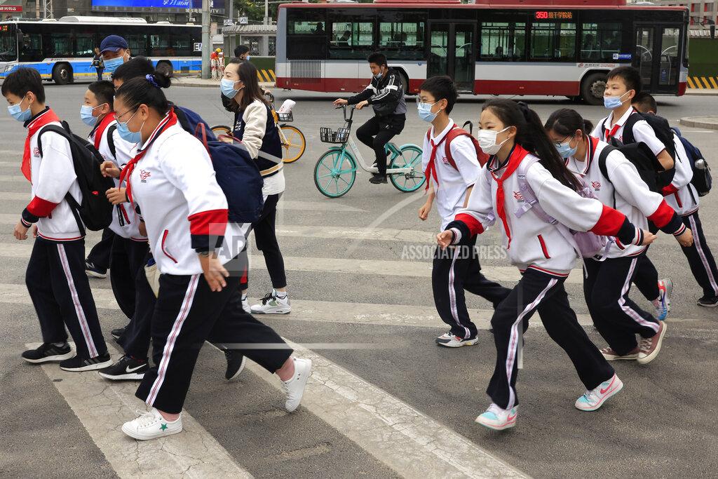 Ng Han Guan School children wearing masks cross a busy traffic intersection in Beijing on Thursday, April 29, 2021. China's population grew last year, the government said Thursday, following a news report a once-a-decade census might have found a decline, possibly adding to downward pressure on economic growth. (AP Photo/Ng Han Guan)