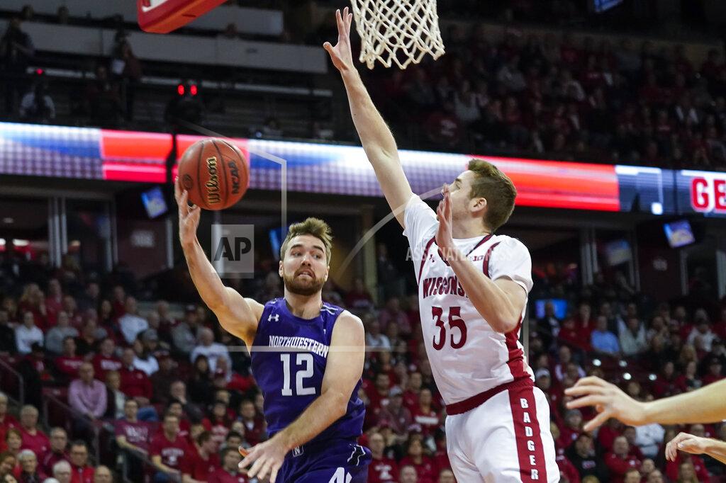 Andy Manis Northwestern's Pat Spencer (12) passes as Wisconsin's Nate Reuvers (35) defends during the first half of an NCAA college basketball game Wednesday, March 4, 2020, in Madison, Wis. (AP Photo/Andy Manis)