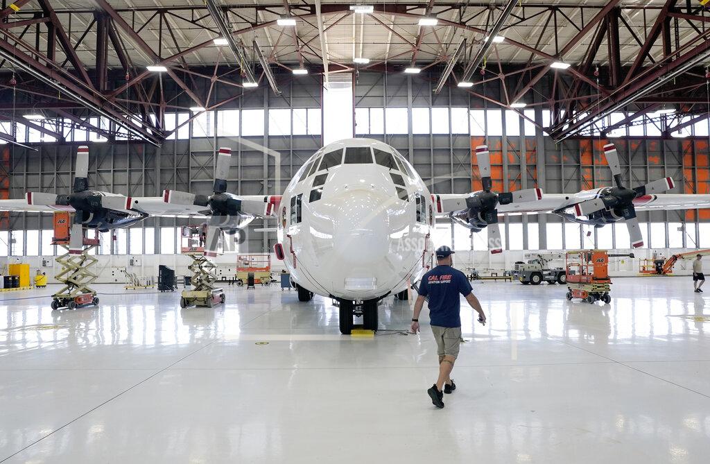 Rich Pedroncelli Aircraft Mechanic Cody Poole walks past one of the recently acquired C-130 aircraft, that will be used for firefighting, hangared at the California Department of Forestry and Fire Protection's Sacramento Aviation Management Unit based at McClellan Airpark in Sacramento, Calif., Friday, July 23, 2021. Firefighters are trying to become smarter in how they prepare for the drought- and wind-driven wildfires that have become more dangerous across the American West in recent years, including by adding aircraft like the Sikorsky Firehawk helicopters or military surplus C-130 transport aircraft retrofitted to drop fire retardant. (AP Photo/Rich Pedroncelli)