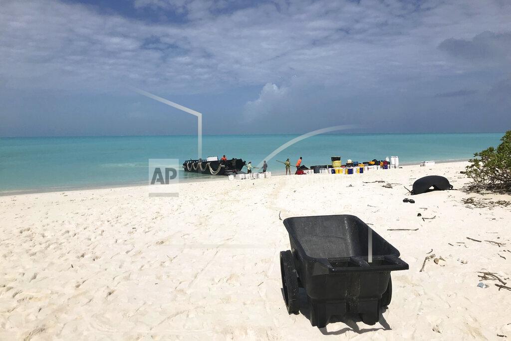 In this March 2, 2020, photo provided by Naomi Worcester, a crew of workers unload gear as they arrive on Kure Atoll in the Northwestern Hawaiian Islands, one of the most remote places on Earth. Cut off from the rest of the planet since February, four environmental field workers are back, re-emerging into a changed society by the coronavirus outbreak. (Naomi Worcester/Hawaii Department of Land and Natural Resources via AP)