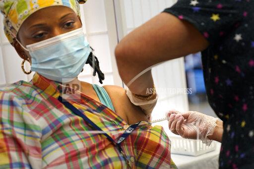 Shyrel Ritter, a certified nursing assistant at the Hebrew Home at Riverdale, receives her COVID-19 booster shot at her workplace in New York, Monday, Sept. 27, 2021. The deadline for hospital and nursing home workers in New York state to be vaccinated against COVID-19 arrived Monday with the prospect of severe staff shortages fueled by workers getting suspended or fired for refusing to be inoculated. All health care workers in New York state at hospitals and nursing homes are required to be vaccinated with at least one dose of the COVID-19 vaccine by Monday. (AP Photo/Seth Wenig)