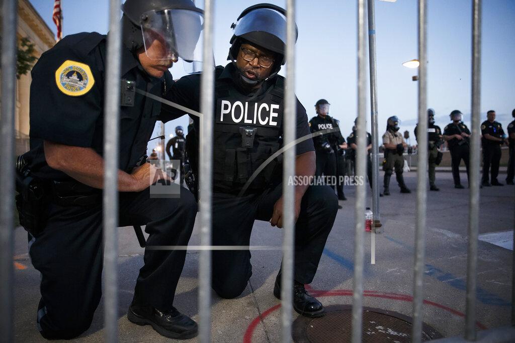 Brian Powers Senior police officers Irvin Franklin and Jack Kamerick kneel and say a prayer behind police lines on Sunday, May 31, 2020 in Des Moines. Answering a call from the protestors, the rest of the officers kneeled and the protest peacefully disbanded shortly thereafter. (Brian Powers/The Des Moines Register via AP )