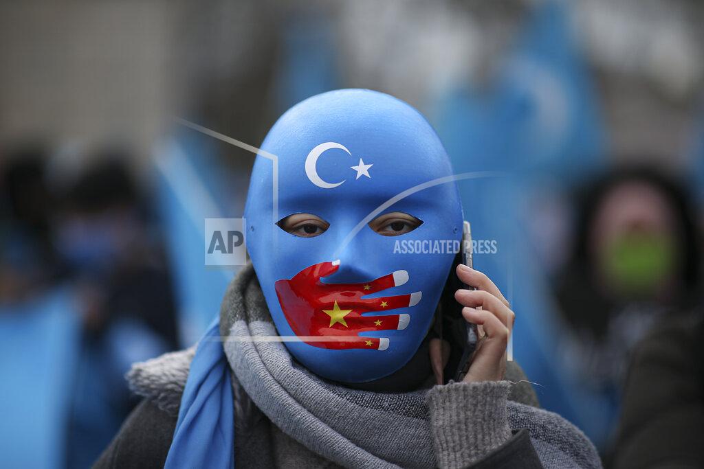 Emrah Gurel A protester from the Uyghur community living in Turkey, wearing a mask with a Chinese flag uses a mobile phone during a protest in Istanbul, Thursday, March 25, against against the visit of China's FM Wang Yi to Turkey. Hundreds of Uyghurs staged protests in Istanbul and the capital Ankara, denouncing Wang Yi's visit to Turkey and demanding that the Turkish government take a stronger stance against human rights abuses in China's far-western Xinjiang region. (AP Photo/Emrah Gurel)