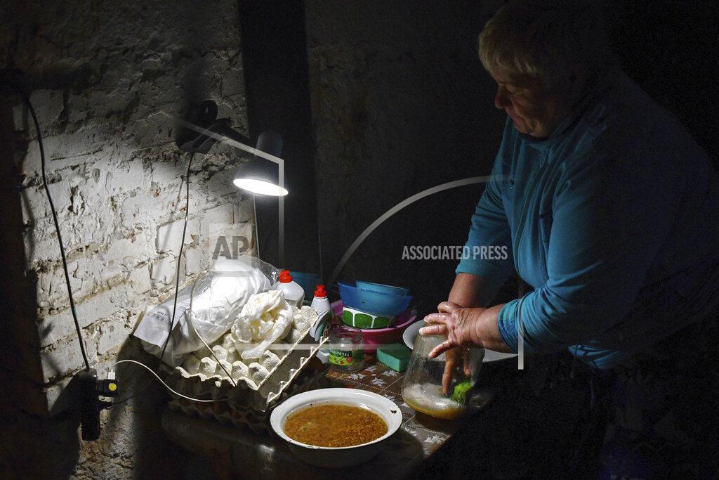Andriy Andriyenko An Ukrainian woman washes dishes in the basement of a building used as bomb shelter in Soledar, Donetsk region, Ukraine, Tuesday, May 24, 2022. (AP Photo/Andriy Andriyenko)