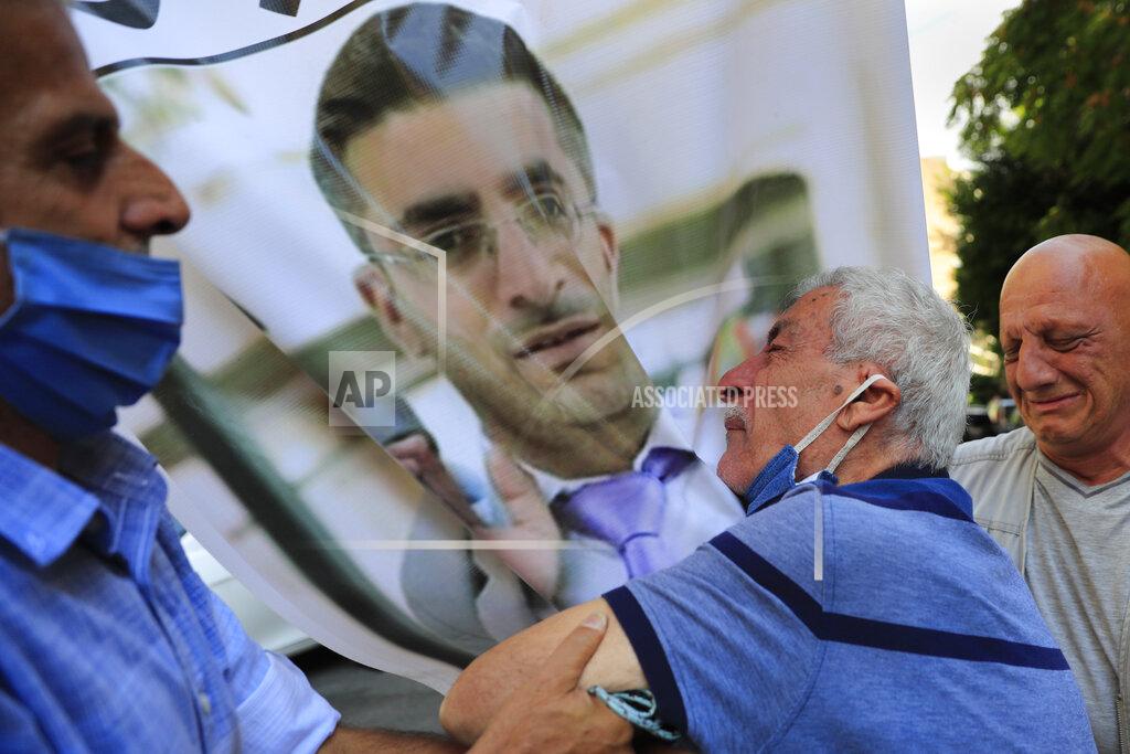 Hussein Malla The father of Ibrahim Harb, 35, center, a Lebanese man who was critically injured in the massive explosion at Beirut's port last year and who died on Monday nearly 14 months after the blast, mourns on his son's portrait during his funeral procession, in Beirut, Lebanon, Tuesday, Sept. 28, 2021. On Aug. 4, 2020, hundreds of tons of ammonium nitrate, a highly explosive material used in fertilizers, ignited after a massive fire at the port. The death brings to at least 215 the number of people who have been killed by the blast, according to official records. (AP Photo/Hussein Malla)