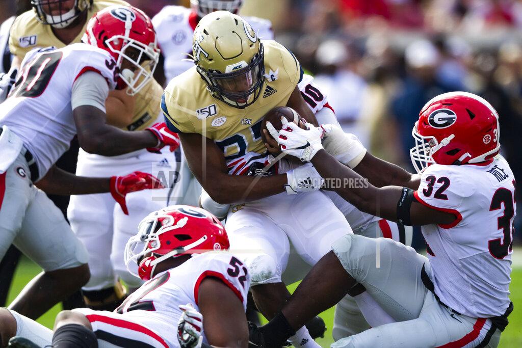 FILE - In this Nov. 30, 2019, file photo, Georgia Tech running back Jordan Mason (27) tries to evade a tackle as Georgia linebacker Monty Rice (32) holds on during the first half of an NCAA college football game in Atlanta. The Southeastern Conference's conference-only scheduling decision during the coronavirus pandemic wiped out any hopes of saving four in-state rivalries against Atlantic Coast Conference opponents, all traditionally played on the final Saturday of the regular season. (AP Photo/John Amis, File)