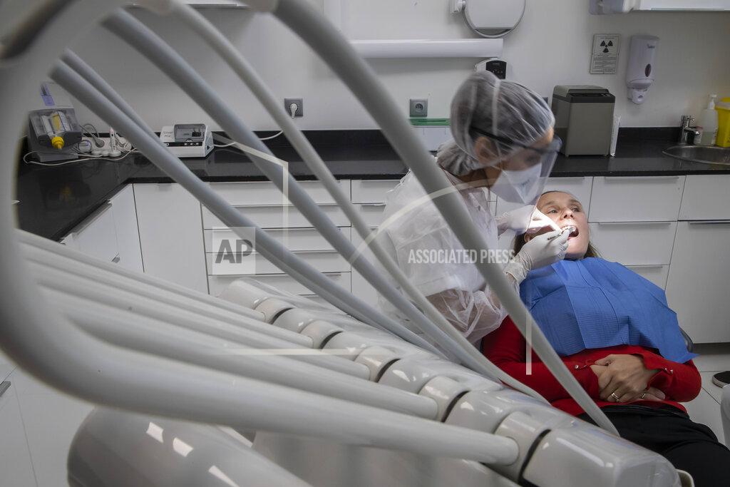 Michel Euler In this Wednesday, May 13, 2020 photo, dentist Sabrine Jendoubi, left, inspects the teeth of patient Veronique Guillot, during a dental appointment at a dental office in Paris. Those with toothache that suffered through France's two-month lockdown, finally have hope to end the pain. Dental practices are cautiously re-opening and non-emergency dentist appointments are now permitted around the country, as the French government eased confinement restrictions from Monday. (AP Photo/Michel Euler)