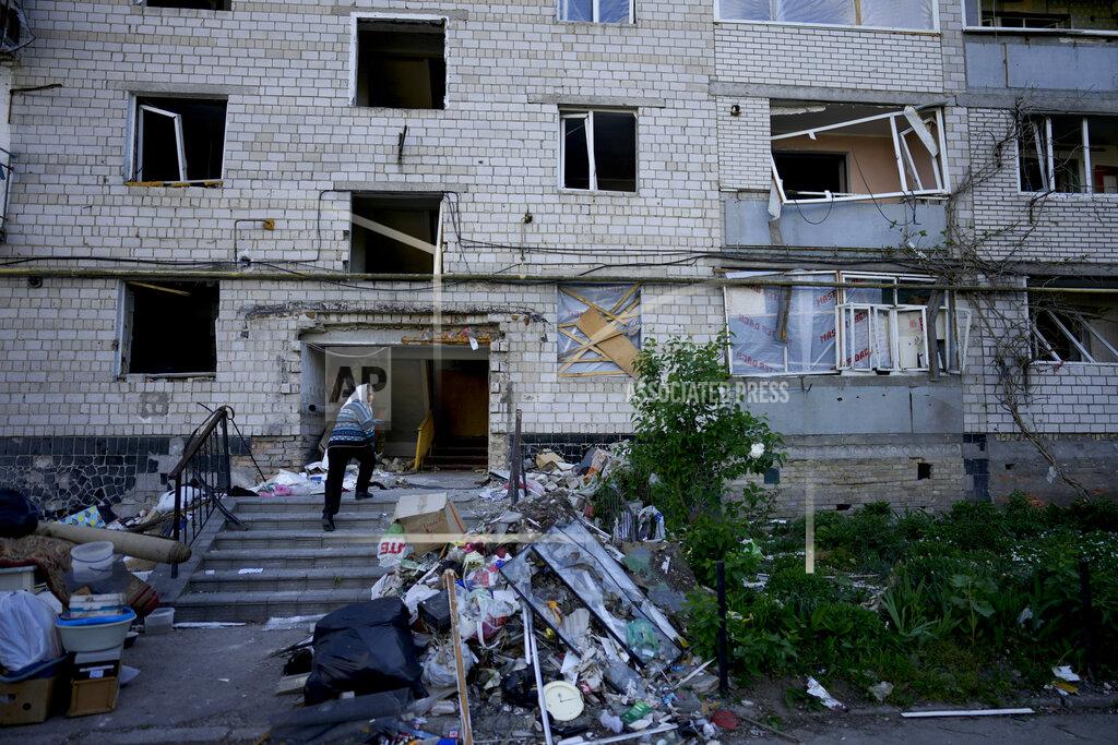 Natacha Pisarenko A residents enters her home building ruined by shelling in Borodyanka, Ukraine, Tuesday, May 24, 2022. No matter where Ukrainians live, the 3-month-old war never seems to be far away. Those in towns and villages near the front lines hide in basements from constant shelling, struggling to survive with no electricity or gas — and often no running water. (AP Photo/Natacha Pisarenko)