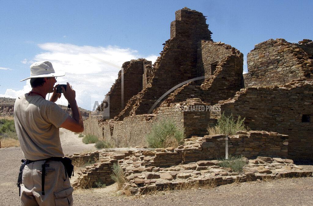 FILE - In this Aug. 10, 2005, file photo, tourist Chris Farthing, from Suffolks County, England, takes a picture of Anasazi ruins in Chaco Culture National Historical Park in New Mexico. U.S. Interior Secretary David Bernhardt says he'll extend the public comment period on a contested plan that will guide oil and gas drilling and other development in an area of New Mexico that includes a national park and locations important to Native American tribes. (AP Photo/Jeff Geissler, File)