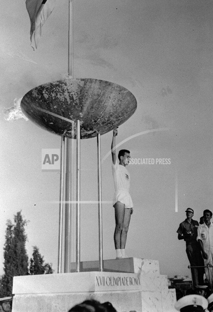 Uncredited Italian student Giancarlo Peris holds the torch after lighting the Olympic flame in the tall tripod brazier on the perimeter of the Olympic Stadium in Rome, Aug. 25, 1960, at the formal opening of the XVII modern Olympiad. (AP Photo)