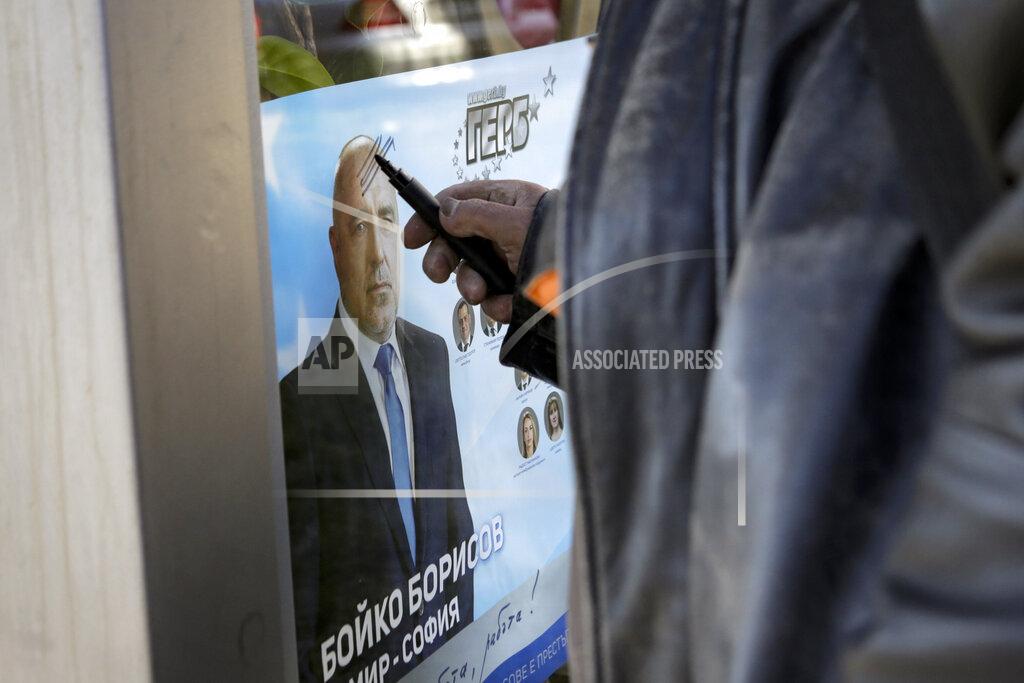 Valentina Petrova A man draws on poster of Bulgarian prime minister Boyko Borissov in Sofia, Bulgaria, Wednesday, March 31, 2021. After months of nationwide anti-government protests over corruption, stalled reforms and a stagnating economy in the EU's poorest member state, Bulgarians are gearing up for a parliamentary election overshadowed by a deadly pandemic. (AP Photo/Valentina Petrova)