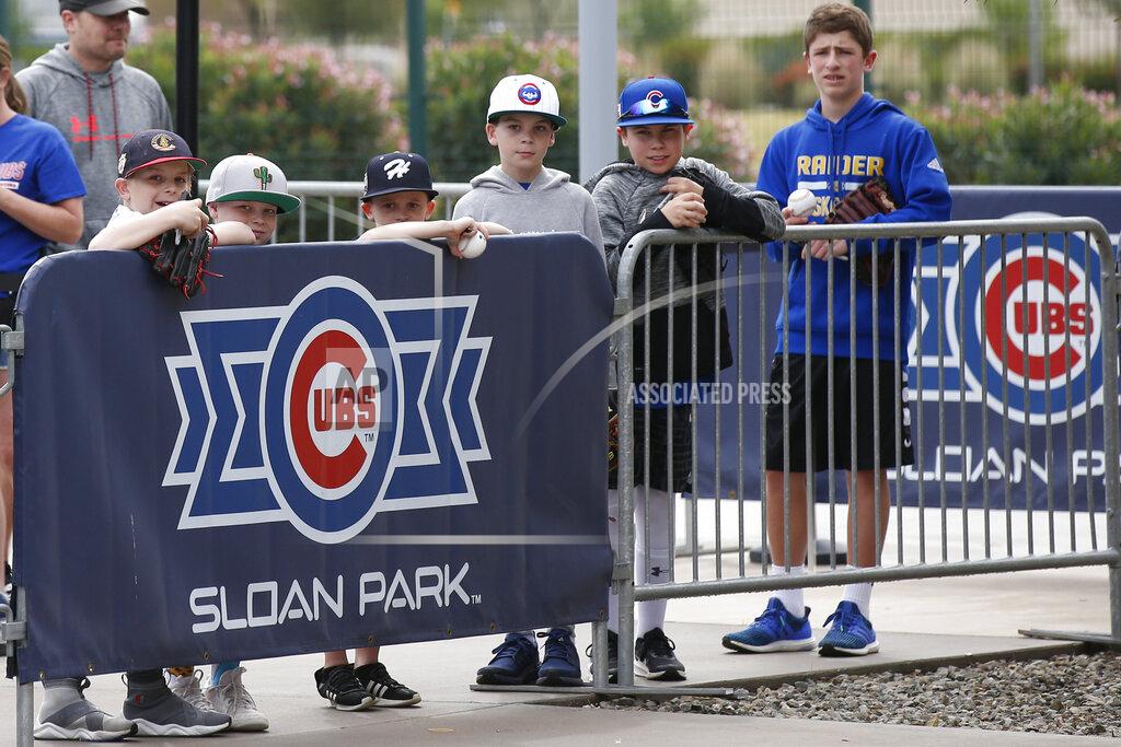 Sue Ogrocki FILE - Young fans look out to the practice fields after a spring training baseball game between the Los Angeles Dodgers and the Chicago Cubs was canceled for inclement weather, at Sloan Park in Mesa, Ariz., in this Thursday, March 12, 2020, file photo. Big league managers say that Major League Baseball has instructed them to prepare for spring training to start on time in mid-February despite uncertainty around the coronavirus. Tampa Bay Rays manager Kevin Cash said Wednesday, Dec. 16, 2020, that officials from the commissioner's office had a meeting with managers Tuesday an expressed optimism about opening spring camps as scheduled. (AP Photo/Sue Ogrocki, File)