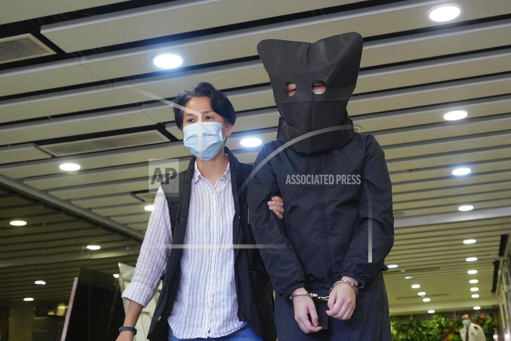 Vincent Yu A hooded suspect is accompanied by a police officer to search evidence at office in Hong Kong Thursday, July 22, 2021. Hong Kong's national security police on Thursday arrested five people from a trade union of the General Association of Hong Kong Speech Therapists on suspicion of conspiring to publish and distribute seditious material, in the latest arrests made amid a crackdown on dissent in the city. (AP Photo/Vincent Yu)
