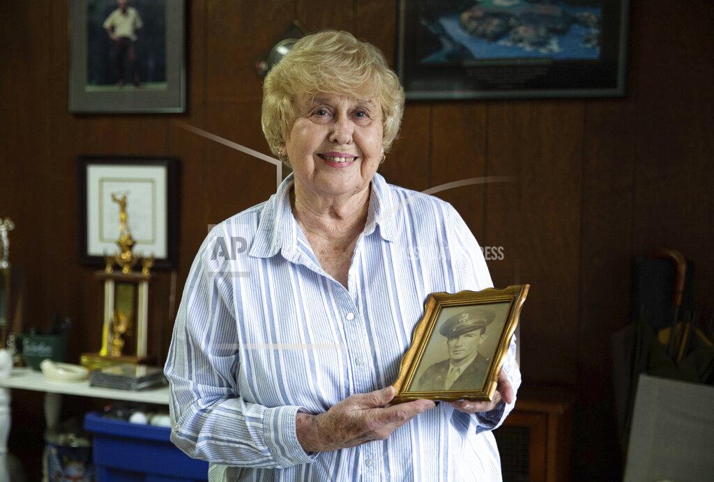 Grace Ramey Velda Alexander of Bowling Green, Ky., holds a portrait of her father U.S. Army 2nd Lt. Johnnie Elmore while going through the contents of his military footlocker trunk in her garage on Wednesday, Sept. 15, 2021, after she and her family found the trunk in her grandmother's old country store in Round Hill last week after it had been missing for nearly 77 years. Elmore, who graduated ROTC at Western Kentucky University in 1941, was killed in action in December 1944 at the age of 31 while based in France and England during World War II. The trunk contains a World War II uniform, a folded American flag, a Purple Heart and other medals and patches, dog tags, love letters to his soon-to-be wife Irene Martin, diaries and more. (Grace Ramey/Bowling Green Daily News via AP)