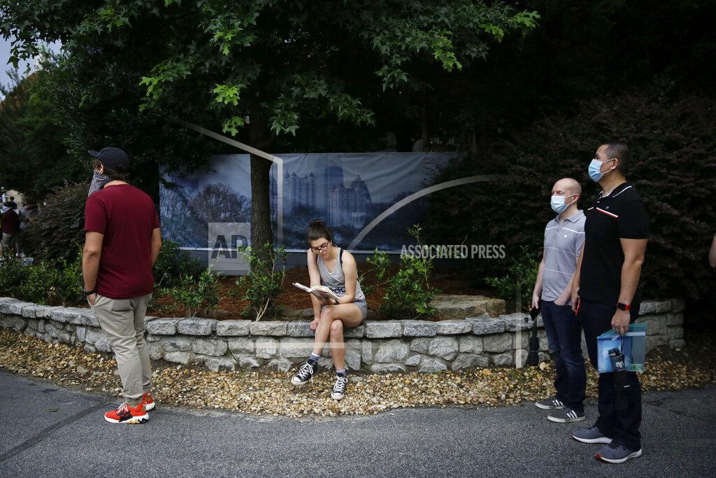 Brynn Anderson A person reads a book as they wait in line to vote in the Georgia's primary election at Park Tavern on Tuesday, June 9, 2020, in Atlanta. (AP Photo/Brynn Anderson)