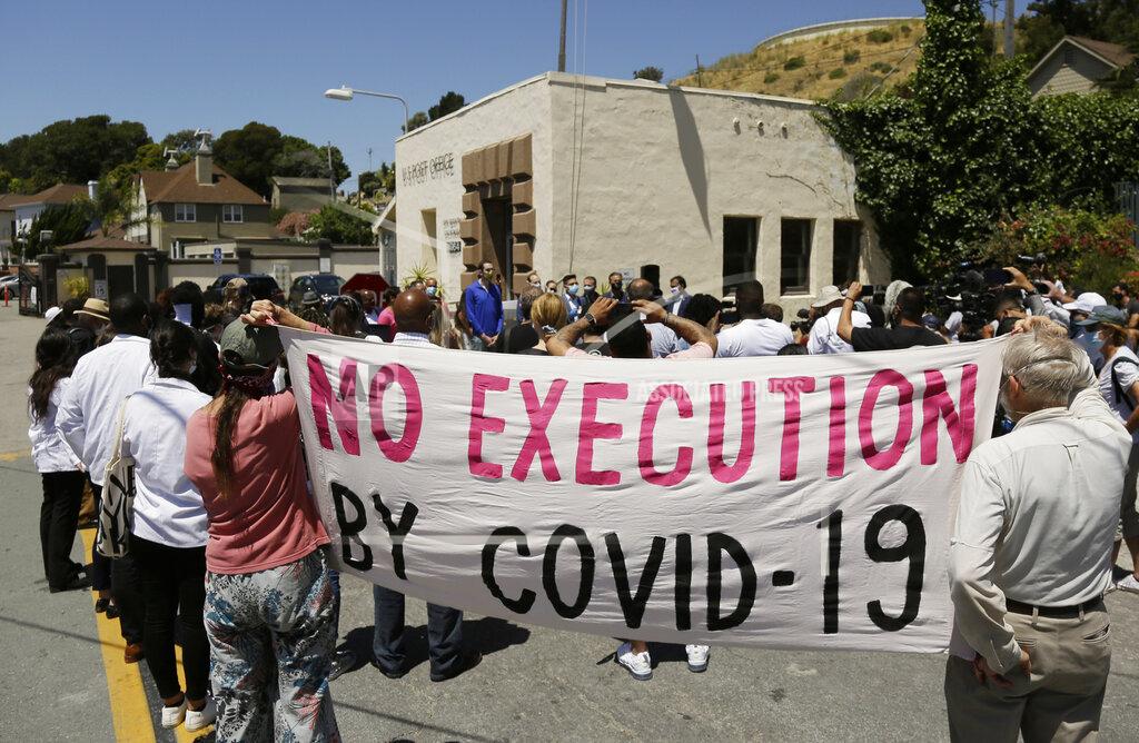 Eric Risberg FILE - In this July 9, 2020, file photo, people hold up a banner while listening to a news conference outside San Quentin State Prison in San Quentin, Calif. One in five state and federal prisoners in the United States has tested positive for the coronavirus, a rate more than four times higher than the general population. In some states, more than half of prisoners have been infected, according to data collected by The Associated Press and The Marshall Project. (AP Photo/Eric Risberg, File)