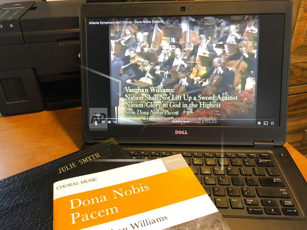 In this Monday, June 8, 2020, photo, a piece of music by Ralph Vaughan Williams is displayed in Worthington, Ohio, in front of a YouTube video of the Atlanta Symphony performing it. The coronavirus pandemic has forced choral singers to raise their single voices in song from isolated settings, singing to audio files or online videos rather than with other singers who have the potential of spreading COVID-19. (AP Photo/Julie Carr Smyth)