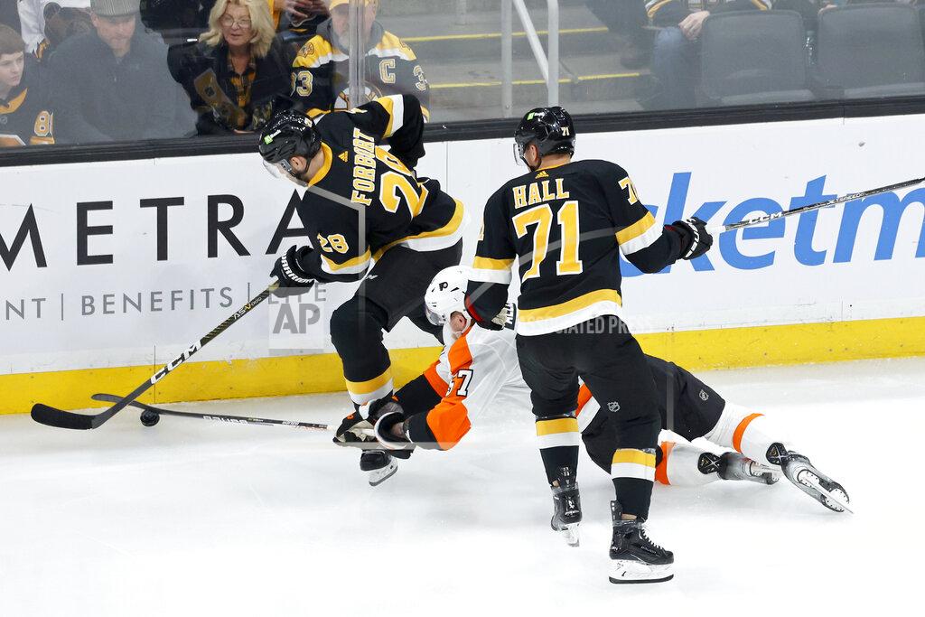 Boston Bruins defenseman Derek Forbort controls the puck ahead of a diving effort from Philadelphia Flyers right wing Wade Allison as Bruins' Taylor Hall (71) looks on during the first period of an NHL hockey game, Monday, Jan. 16, 2023, in Boston. (AP Photo/Mary Schwalm)